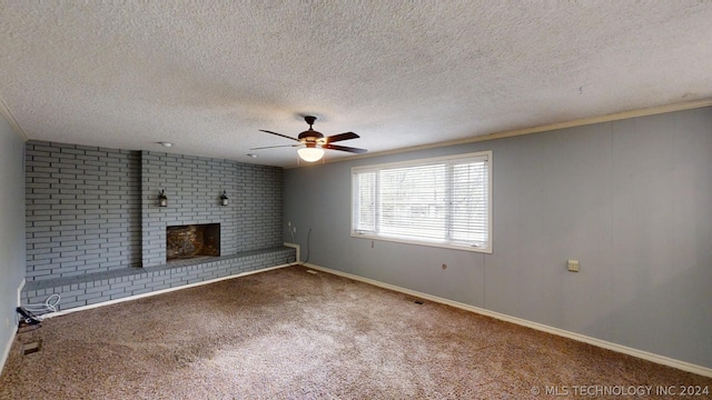 unfurnished living room featuring a textured ceiling, ornamental molding, ceiling fan, a fireplace, and carpet