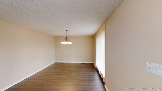 unfurnished dining area featuring dark hardwood / wood-style flooring, a chandelier, and a textured ceiling