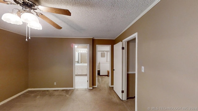 spare room featuring light carpet, ceiling fan, ornamental molding, and a textured ceiling