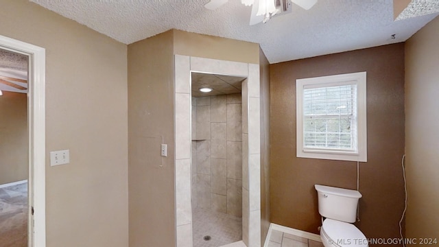 bathroom featuring ceiling fan, tiled shower, a textured ceiling, and toilet