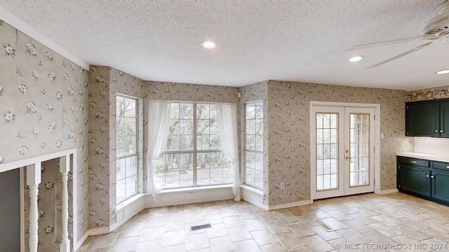 entryway with ceiling fan, a wealth of natural light, french doors, and a textured ceiling