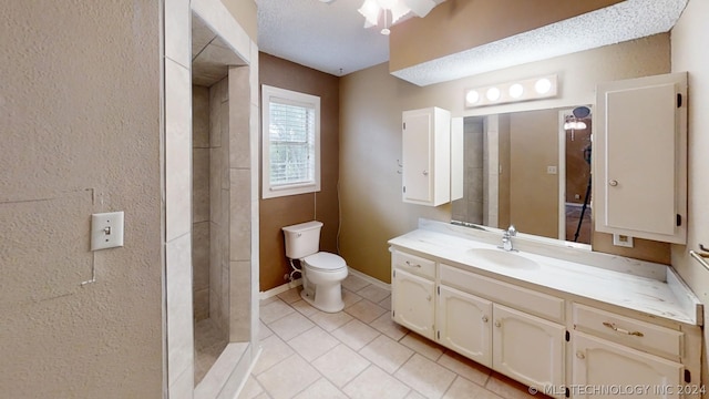 bathroom with vanity, tile patterned flooring, toilet, and tiled shower