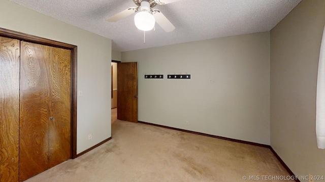 unfurnished bedroom with ceiling fan, light carpet, and a textured ceiling