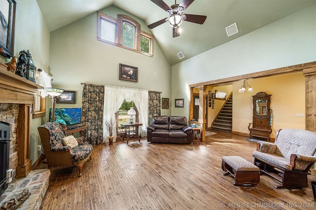 living room featuring high vaulted ceiling, hardwood / wood-style flooring, a fireplace, and ceiling fan