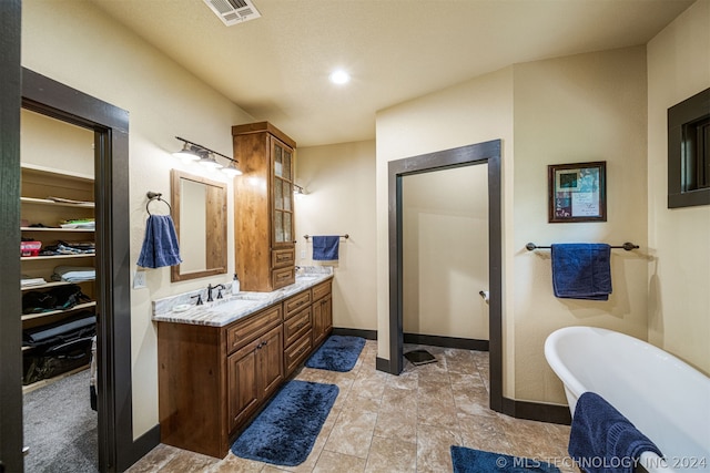 bathroom with dual vanity, tile floors, and a bathing tub