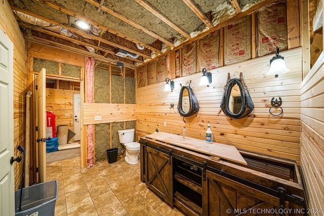 interior space with tile floors, wood walls, vanity, and toilet