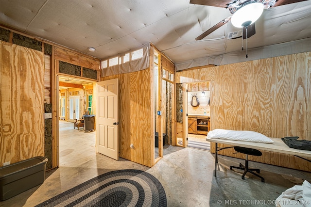 home office with wood walls, concrete floors, and ceiling fan