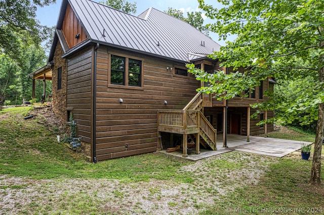 back of house featuring a patio, a wooden deck, and a lawn