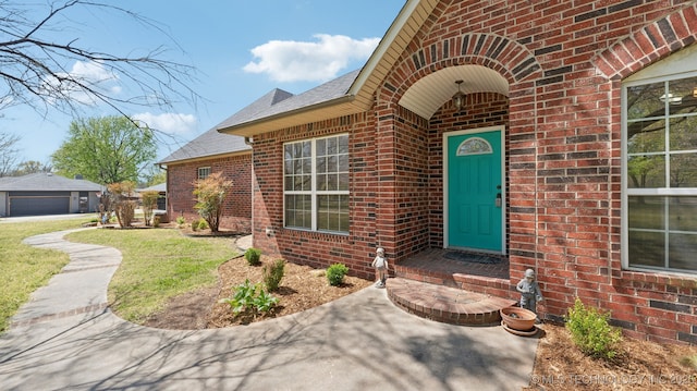 1805 College Park Rd, Claremore, OK 74017 - doorway to property featuring brick siding, roof with shingles, a yard, and a garage