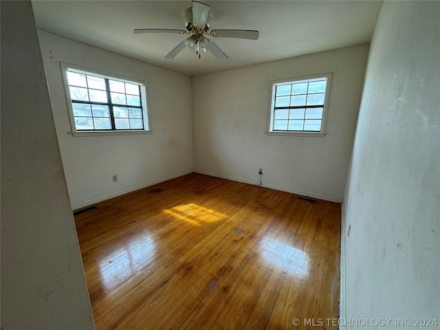 spare room with a healthy amount of sunlight, wood-type flooring, and ceiling fan