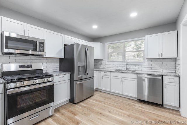 kitchen with stainless steel appliances, light wood finished floors, a sink, and white cabinetry