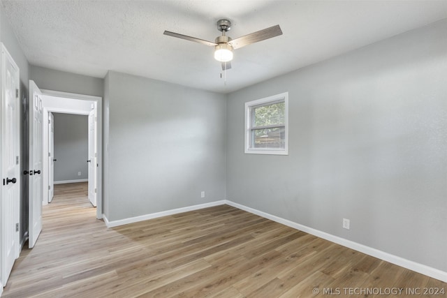 unfurnished room with light wood-style floors, ceiling fan, a textured ceiling, and baseboards