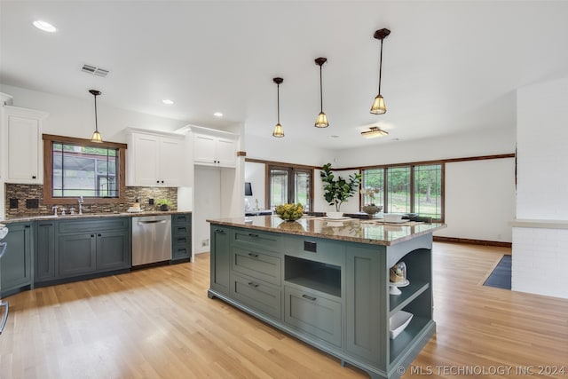 kitchen with stainless steel dishwasher, white cabinetry, decorative light fixtures, and dark stone countertops