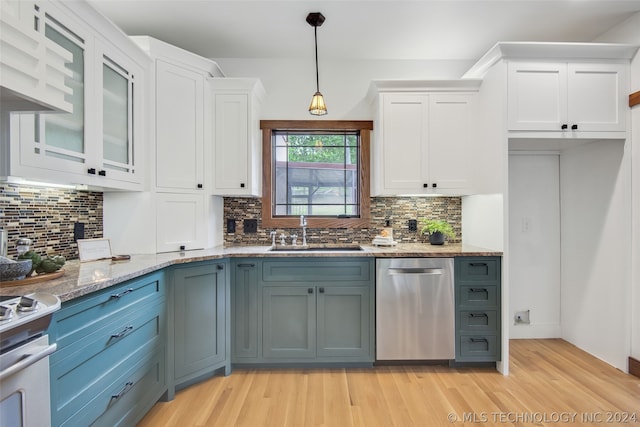 kitchen featuring white cabinets, stainless steel dishwasher, sink, and light stone counters