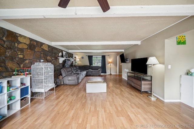 living room featuring ceiling fan, beam ceiling, light hardwood / wood-style flooring, and a textured ceiling