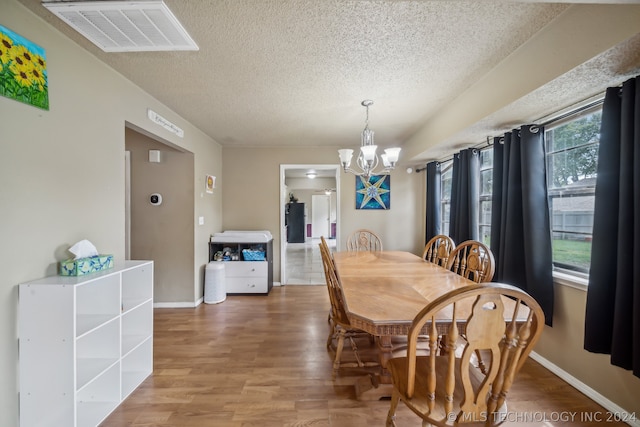 dining room with a notable chandelier, hardwood / wood-style floors, and a textured ceiling