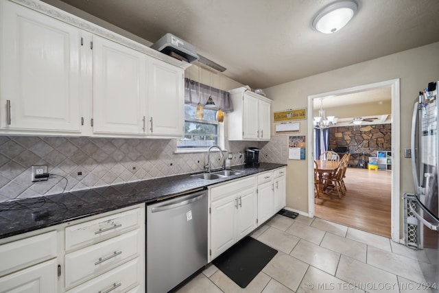 kitchen with appliances with stainless steel finishes, tasteful backsplash, sink, light tile patterned floors, and white cabinetry