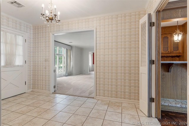 foyer with light colored carpet, a chandelier, and ornamental molding