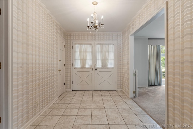 carpeted foyer entrance featuring crown molding, french doors, and a chandelier