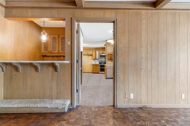 kitchen featuring a breakfast bar, appliances with stainless steel finishes, decorative light fixtures, and wood walls