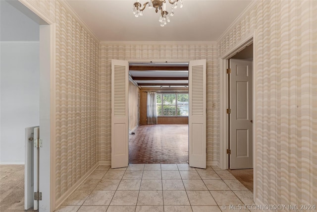 hall featuring a chandelier, light tile patterned floors, and crown molding