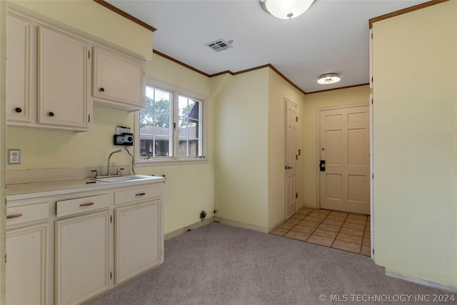 laundry area featuring cabinets, crown molding, sink, and light carpet