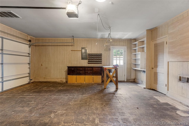 garage featuring electric panel, wooden walls, and a garage door opener