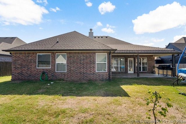 rear view of property with a yard, a patio, and a jacuzzi