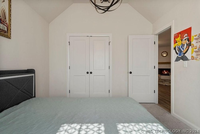 bedroom featuring lofted ceiling, light carpet, and a closet