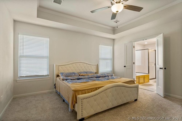 bedroom featuring light carpet, connected bathroom, a raised ceiling, and ceiling fan