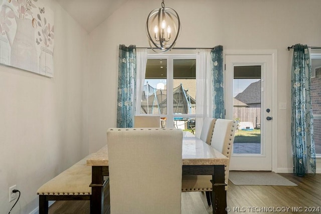 dining area featuring a notable chandelier, wood-type flooring, and vaulted ceiling