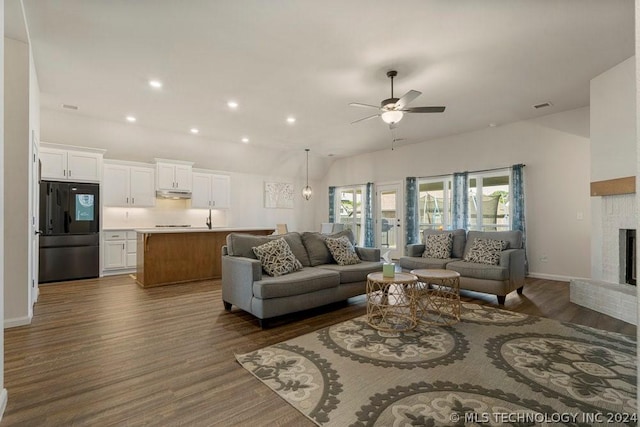 living room featuring a brick fireplace, dark hardwood / wood-style floors, and ceiling fan