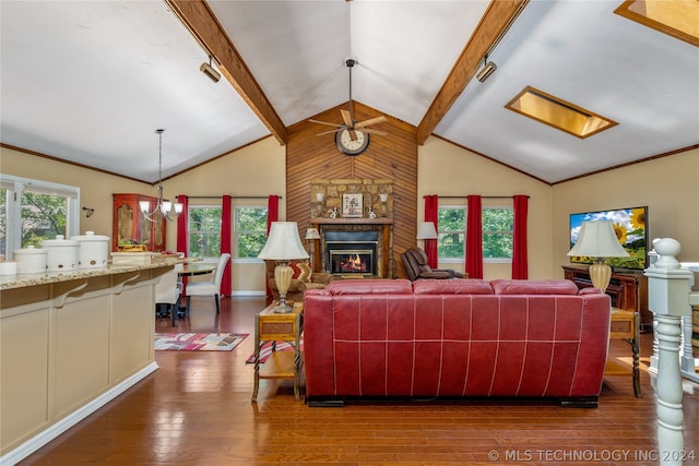 living room featuring lofted ceiling with beams, ceiling fan with notable chandelier, a large fireplace, and hardwood / wood-style flooring