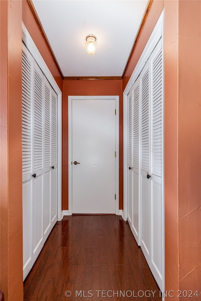 hallway with ornamental molding and dark wood-type flooring