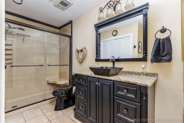 bathroom with a shower with shower door, tile flooring, vanity, and toilet