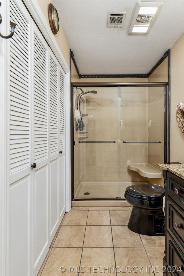 bathroom featuring a shower with shower door, tile flooring, vanity, and toilet