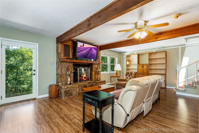 living room with beam ceiling, a stone fireplace, ceiling fan, and hardwood / wood-style floors