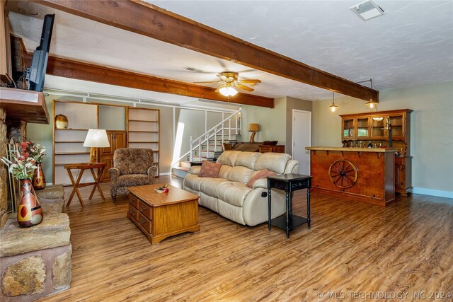 living room featuring beam ceiling, hardwood / wood-style flooring, and ceiling fan