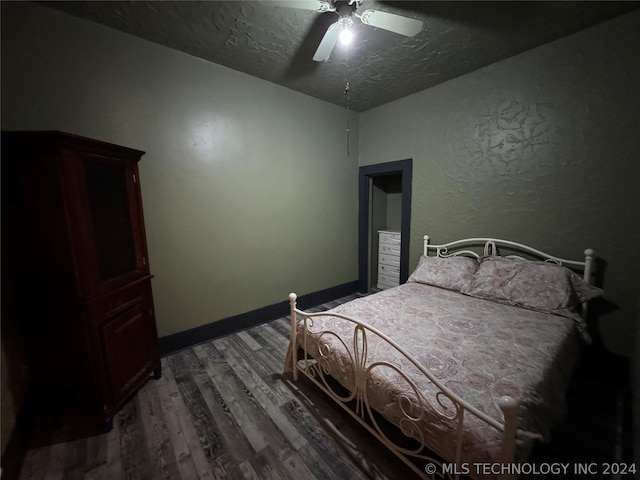 bedroom with a textured ceiling, ceiling fan, and dark hardwood / wood-style floors