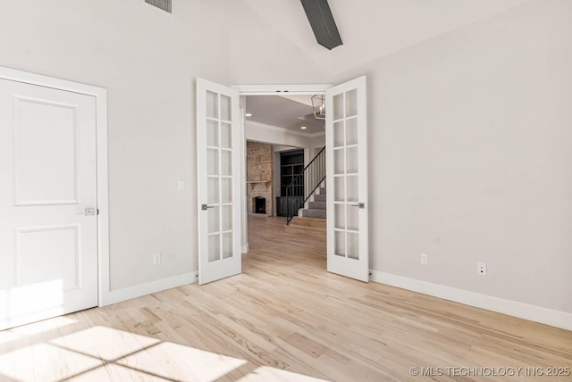 spare room featuring hardwood / wood-style flooring, high vaulted ceiling, and french doors