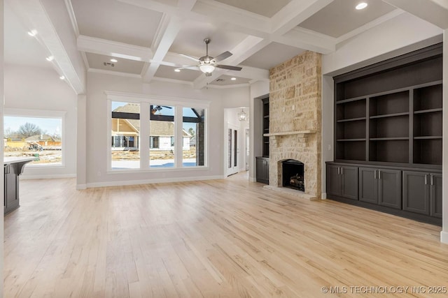 unfurnished living room featuring coffered ceiling, a stone fireplace, a wealth of natural light, and beam ceiling