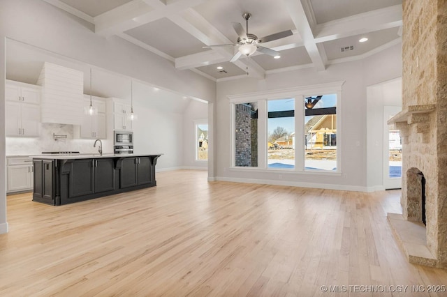 living room with beamed ceiling, plenty of natural light, and light hardwood / wood-style floors