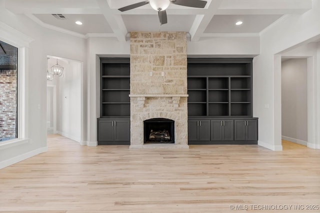 unfurnished living room with coffered ceiling, a stone fireplace, beam ceiling, and light wood-type flooring