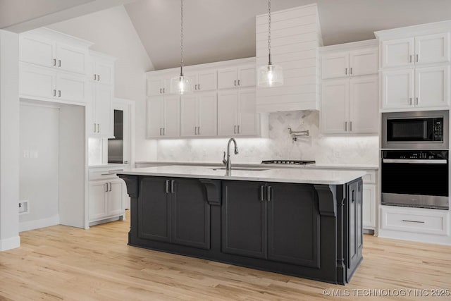 kitchen with wall oven, white cabinetry, a kitchen island with sink, and built in microwave