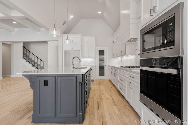 kitchen with stainless steel appliances, an island with sink, and white cabinets