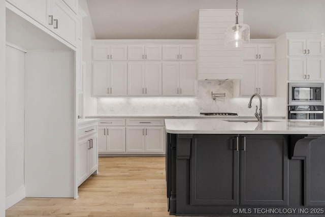 kitchen featuring sink, light wood-type flooring, pendant lighting, stainless steel appliances, and white cabinets