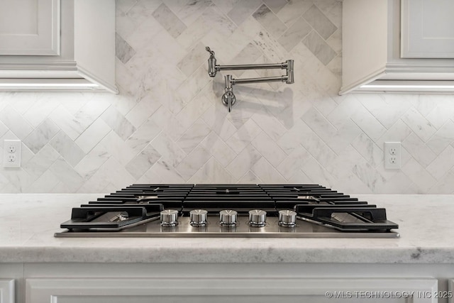 kitchen with stainless steel gas stovetop, white cabinetry, and light stone counters