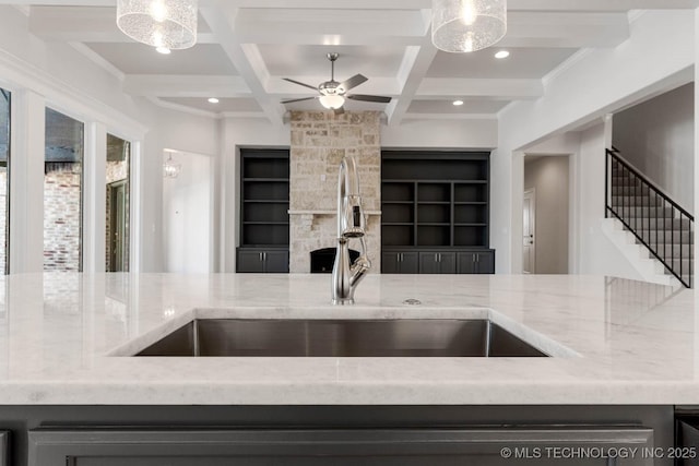 kitchen with sink, hanging light fixtures, beam ceiling, coffered ceiling, and built in shelves