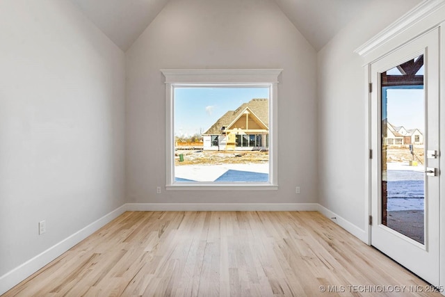 unfurnished room with vaulted ceiling and light wood-type flooring