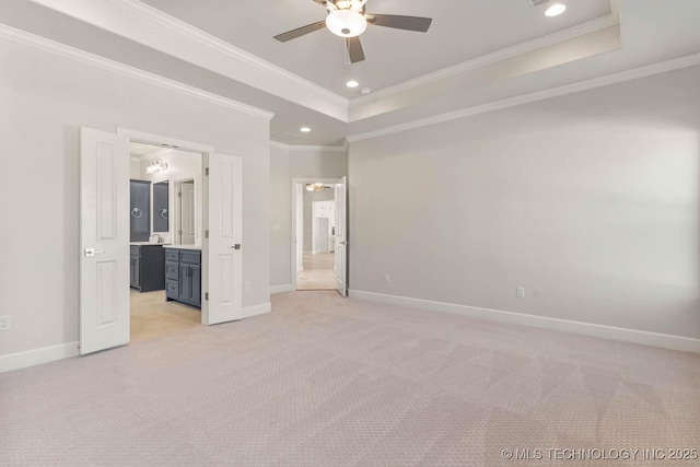 unfurnished bedroom featuring light colored carpet, ceiling fan, a raised ceiling, crown molding, and ensuite bath